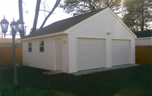 Garage with a roof and white vinyl siding and windows